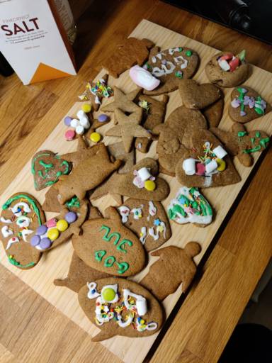 En skärbräda med hemmagjorda pepparkakor, med glasyr och godis i olika färger